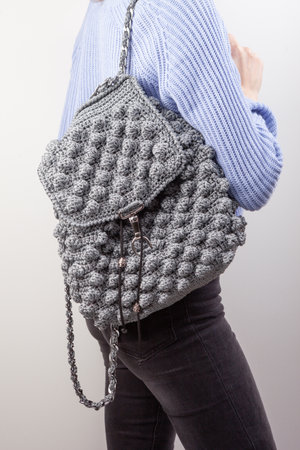 Woman with knitted backpack on gray backgroundの写真素材