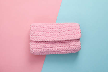 Hand made knitted pink wallet on blue pink pastel background