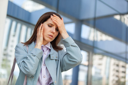 headache. Young business woman holding her head on the background of the business centerの写真素材