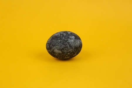 Gray marble painted Easter egg on yellow backgroundの写真素材