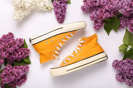 Sneakers with branches of blooming lilacs on white background. spring concept. top view. flat lay