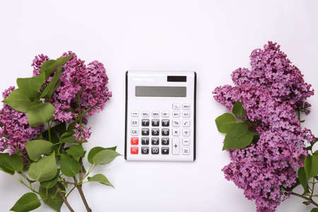Calculator with branches of blooming lilacs on white background. top view. flat layの写真素材