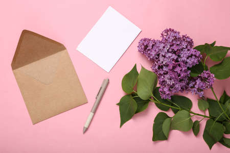 Envelope with branches of blooming lilacs on pink background. spring concept. top view. flat lay
