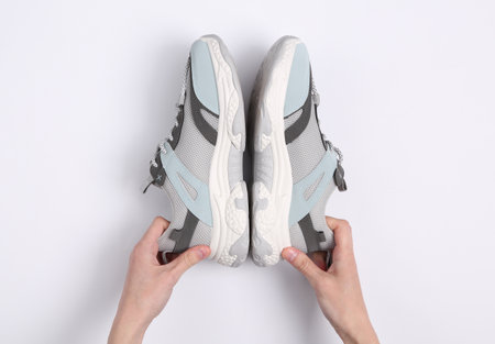 Hands hold fashion sport sneakers on white background