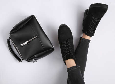 Women's legs in boots and a black leather bag on a white background. fashion concept. top viewの写真素材
