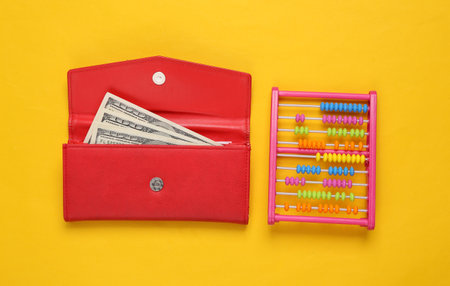 Wallet with dollar bills and toy abacus on yellow backgroundの写真素材
