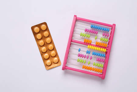 Toy abacus with blister pills on white background. top view