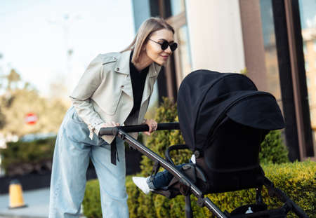 Stylish loving mom walks with a stroller in the city location. Maternity, lifestyleの写真素材