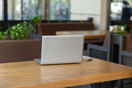 Laptop with smartphone on table of outdoor cafe