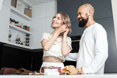 Young attractive woman tries on earrings presented by her loving husband in the kitchen. Romantic, love conceptの写真素材