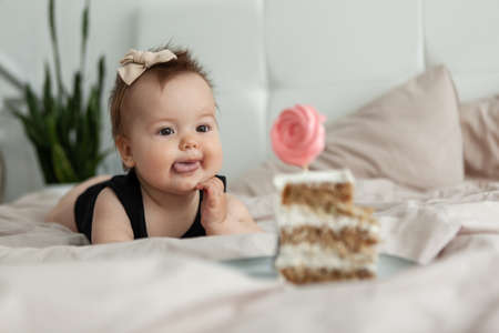 Little funny baby girl crawls on the bed to a piece of delicious cake. birthday