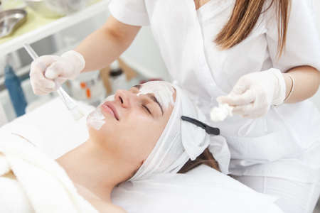 cosmetic procedures. Beauty salon, doctor in gloves applies mask for beautiful woman with closed...