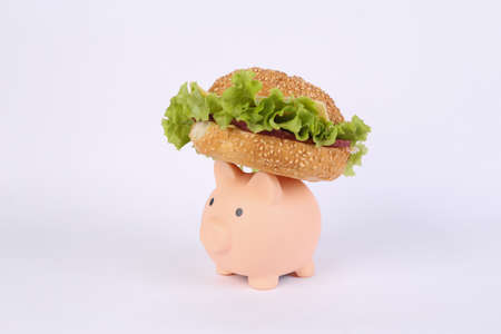 Appetizing burger and piggy bank on white background.の写真素材