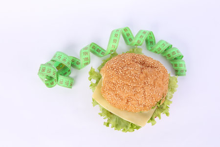 Appetizing burger with measuring tape on white background. weight loss conceptの写真素材