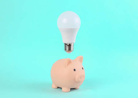 Piggy Bank With A Flying Light Bulb On A Blue Background. Minimal idea, inspiration conceptの写真素材