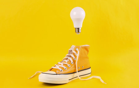 Retro classic sneaker with a floating light bulb on a yellow background. Minimal, idea, concept art