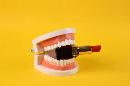 Lipstick in teeth of jaw model. yellow background. beauty minimal conceptの写真素材