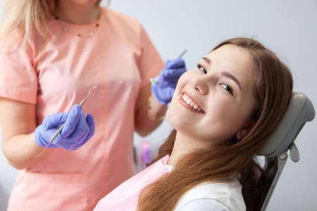 Portrait of a cute smiling woman sitting in medical chair on examination by dentist in dental clinic. Your smile is beautiful! Dental care conceptの写真素材