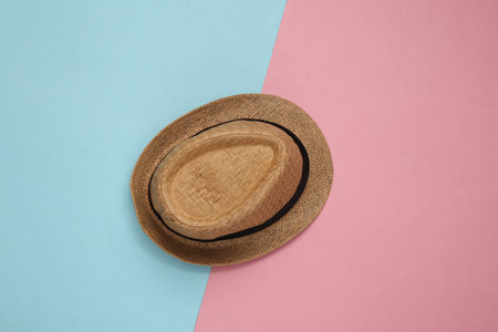Straw hat on blue pink pastel background. top view