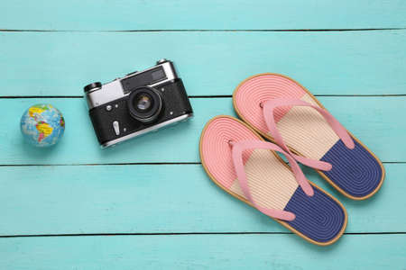 Colored flip flops with travel accessories on blue wooden background. Beach vacation concept. flat layの写真素材