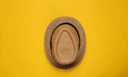 Straw hat on yellow background. top view