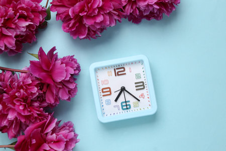 Pink peonies with clock on a blue background. top view. flat layの写真素材