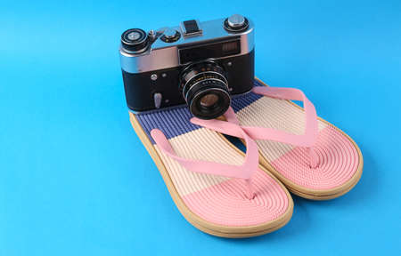 Colored flip flops with camera on blue background. Beach vacation concept.の写真素材