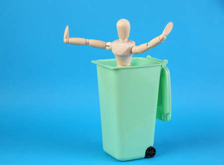 Wooden puppet in Toy trash can on blue background. Povertyの写真素材
