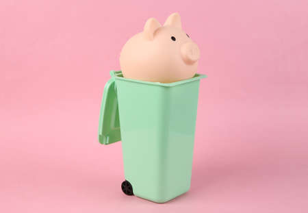 Piggy bank in Toy trash can on pink backgroundの写真素材