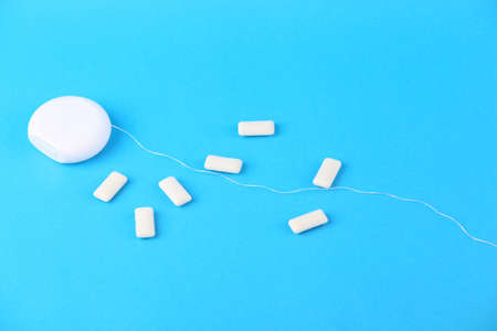 Dental floss and chewing gum pads on a blue background. Dental care concept