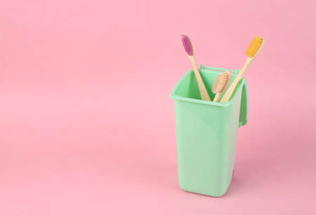 Eco bamboo toothbrushes in trash can on pink backgroundの写真素材