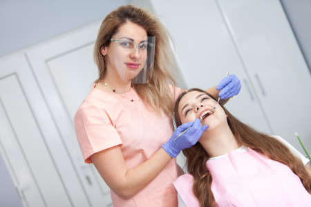 Professional dentist examines beauty woman patient's teeth in a dental clinic. Dental care concept