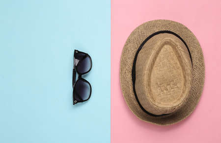 Straw hat and sunglasses on pink blue background. top viewの写真素材