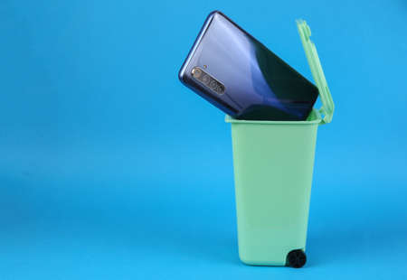 Smartphone in trash can on pink background. Pollution, recycling conceptの写真素材