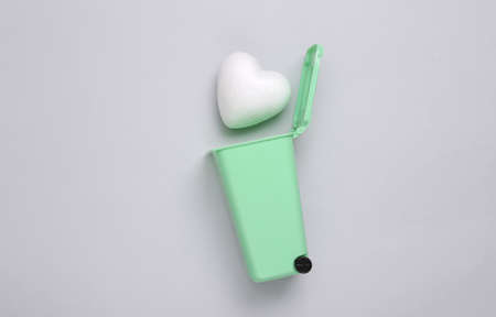 Broken heart concept. Heart in trash can on gray backgroundの写真素材