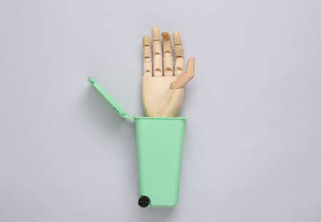 Toy trash can with wooden hand on gray background. Recycling, eco concept. Top view, flat layの写真素材