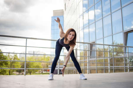 Young fitness woman doing warm up exercises near city building. healthy lifestyleの写真素材