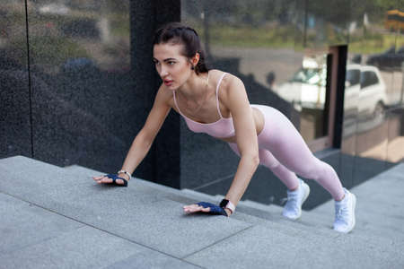 Young athletic woman pushing up stairs in city. street workout