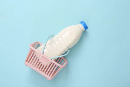 Shopping basket with milk bottle on blue background