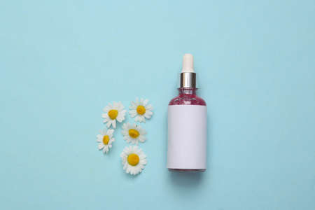 Serum for the face and chamomile flowers on a blue backgroundの写真素材