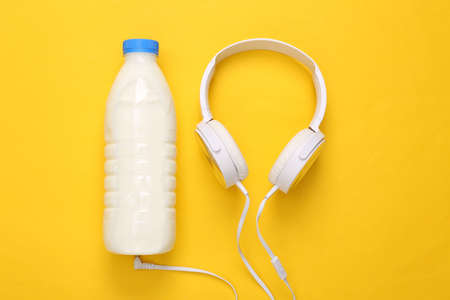 Milk bottle with headphones on yellow background. top viewの写真素材