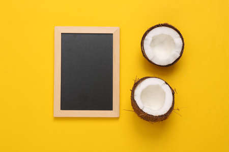 Empty chalk board with coconut halves on yellow background