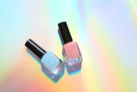 Bottles of nail polish on colored reflective holographic surface