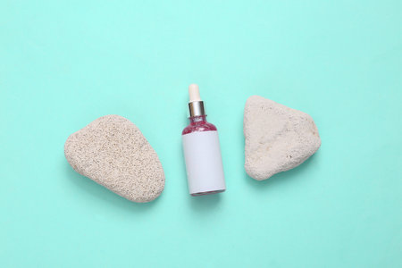 Face serum bottle with natural stones on turquoise backgroundの写真素材