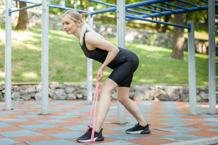 Fit woman works out with fitness rubber bands in workout ground