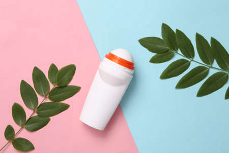Antiperspirant roller with green leaves on blue pink background. top viewの写真素材