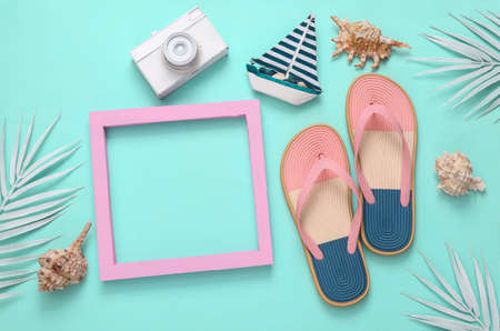 summer layout. Beach accessories with white palm leaves and pink blank frame for text on turquoise backgroundの写真素材