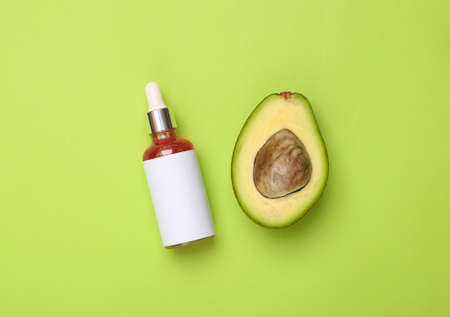 Bottle of face serum and avocado on green background. top viewの写真素材