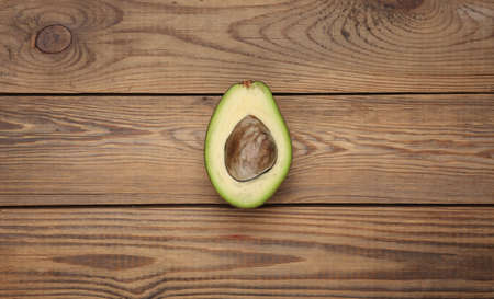 Half ripe avocado fruit on wooden backgroundの写真素材