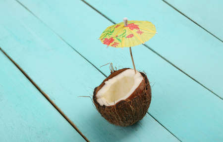 Coconut with umbrella on a blue wooden background. tropical compositionの写真素材